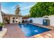 Inviting swimming pool with a fountain feature, surrounded by mature landscaping and a brick patio at 106 E Echo Ln, Phoenix, AZ 85020