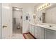 Well-lit bathroom featuring a double vanity, tile floor, and an open doorway to a separate tub area at 10937 N Ventana W Dr, Peoria, AZ 85373