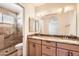 Well-lit bathroom featuring a double sink vanity, and a tiled shower behind glass door at 1202 W Wickieup Ln, Phoenix, AZ 85027