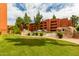 Orange condo building surrounded by a green lawn, trees and fence at 12212 N Paradise Vlg S Pkwy # 113, Phoenix, AZ 85032