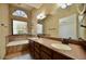 Bathroom with double sinks, bath tub under a arched window and brown countertops at 12965 N 95Th Way, Scottsdale, AZ 85260