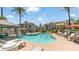 Community pool with lounge chairs, shade and palm trees, set amongst condo buildings under a clear blue sky at 14145 N 92Nd St # 1084, Scottsdale, AZ 85260