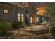 Exterior of a home with a stone facade, arched doorway, and desert landscaping under a sunset sky at 15427 E Firerock Country Club Dr, Fountain Hills, AZ 85268