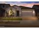 Charming single-story home featuring a manicured front yard and a two-car garage at dusk at 15642 W Georgia Dr, Surprise, AZ 85379