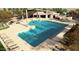 A large outdoor swimming pool with tables, umbrellas, lounge chairs, and a covered building at 15642 W Georgia Dr, Surprise, AZ 85379