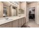 Bathroom featuring a dual sink vanity, decorative mirror, and open closet at 16240 W Talara Way, Surprise, AZ 85374