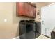 Laundry room showcasing modern front-load washer and dryer with overhead cabinet space at 16245 W Papago St, Goodyear, AZ 85338