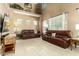 Bright living room with tile floors, two brown leather couches, and many windows at 16245 W Papago St, Goodyear, AZ 85338