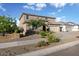 A two-story home with a desert landscape including flowering bushes, an attached two-car garage and a concrete sidewalk at 18381 W La Senda Dr, Surprise, AZ 85387
