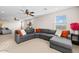 Spacious living room featuring neutral colors, a large sectional sofa, and ceiling fans at 18381 W La Senda Dr, Surprise, AZ 85387