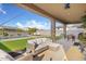 Covered patio with comfortable seating area, dining table, and a view of the pool and turf at 18381 W La Senda Dr, Surprise, AZ 85387