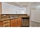 Updated kitchen featuring wood cabinets, granite countertops, a stainless steel dishwasher and a view of the living room at 2025 E Campbell Ave # 248, Phoenix, AZ 85016