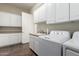 Bright laundry room with white cabinets, sink, and modern GE washer and dryer at 20558 N 263Rd Dr, Buckeye, AZ 85396