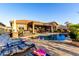 Stunning backyard with a sparkling pool, covered patio, lounge chairs, and lush landscaping at 20558 N 263Rd Dr, Buckeye, AZ 85396