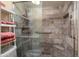 Stylish stone-tiled shower featuring glass door and pebble floor at 2407 W Rue De Lamour Ave, Phoenix, AZ 85029
