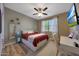 Bedroom with wood look flooring, neutral paint, fan, TV and a white desk at 30446 W Picadilly Rd, Buckeye, AZ 85396