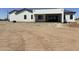 The exterior back of a modern, single-story home with a white exterior, black trim and a covered patio at 31060 N 213Th Dr, Wittmann, AZ 85361