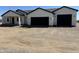 A modern, single-story home with a white exterior, black trim and a two-car garage, set against a desert landscape at 31060 N 213Th Dr, Wittmann, AZ 85361
