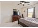 Cozy bedroom with a dark wooden dresser, TV, fan and a comfortable bed with soft carpet flooring at 38659 N Alamo Ct, San Tan Valley, AZ 85140