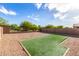 An open gravel backyard is accented by a patch of artificial turf at 39959 W Williams Way, Maricopa, AZ 85138