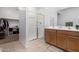 Modern bathroom featuring a dual sink vanity with a glass enclosed shower and a large open closet space at 39959 W Williams Way, Maricopa, AZ 85138