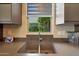 Well-lit kitchen sink area with a modern faucet, gray countertops, and a view of lush greenery at 4714 E Lewis Ave, Phoenix, AZ 85008