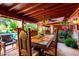 Covered outdoor dining space with a rustic wooden table, chairs, and poolside views for entertaining guests at 6101 E Thunderbird Rd, Scottsdale, AZ 85254