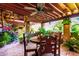 Inviting covered patio with an outdoor table, brick accents, lush foliage, and a ceiling fan at 6101 E Thunderbird Rd, Scottsdale, AZ 85254