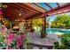 Inviting covered patio boasts an outdoor kitchen, exposed beam construction, pool, and abundant foliage at 6101 E Thunderbird Rd, Scottsdale, AZ 85254