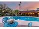 Charming backyard pool area featuring an outdoor dining set and ambient lighting creating a serene oasis for relaxation at 6101 E Thunderbird Rd, Scottsdale, AZ 85254