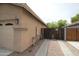 Side view of tan home with garage door and fenced side yard featuring desert landscaping at 7151 W Lamar Rd, Glendale, AZ 85303