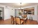 Bright dining room with modern chandelier lighting, wood flooring, and open kitchen access at 7521 S College Ave, Tempe, AZ 85283