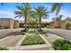 Community entrance featuring palm trees, manicured landscaping, and a paved driveway at 7700 E Gainey Ranch Rd # 124, Scottsdale, AZ 85258