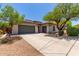 Beige single-story home featuring a large driveway and a well maintained front yard with mature trees at 8647 W Lariat Ln, Peoria, AZ 85383