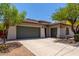 Beige home featuring an attached three-car garage with green doors and a paved driveway at 8647 W Lariat Ln, Peoria, AZ 85383