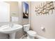 Powder room with pedestal sink, toilet, and neutral wall decor at 8647 W Lariat Ln, Peoria, AZ 85383