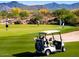 Scenic golf course view with players, a golf cart, and lush green fairways against mountain backdrop at 9543 E Kiisa Dr, Scottsdale, AZ 85262