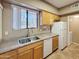 Bright kitchen with double sink, tile floors, white appliances, and wooden cabinets at 10401 N Saguaro Blvd # 123, Fountain Hills, AZ 85268
