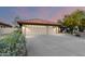 Spacious three-car garage with large driveway and desert landscaping, illuminated by dusk lighting at 13533 N 91St Way, Scottsdale, AZ 85260
