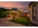 Backyard at dusk featuring a putting green, outdoor kitchen, and string lights creates an enchanting ambiance at 15665 W Coronado Rd, Goodyear, AZ 85395