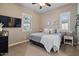 Well-lit bedroom with ceiling fan, TV, two windows, a queen bed, and neutral-toned walls and carpet at 15665 W Coronado Rd, Goodyear, AZ 85395