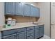 Laundry room with blue cabinetry, white countertops, stainless steel sink, and gray tile floors at 15665 W Coronado Rd, Goodyear, AZ 85395