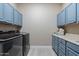 Laundry room with blue cabinetry, white countertops, gray tile floors and modern washer and dryer at 15665 W Coronado Rd, Goodyear, AZ 85395