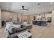 Spacious living room with a modern kitchen featuring stainless steel appliances and a large gray sectional sofa at 15665 W Coronado Rd, Goodyear, AZ 85395