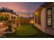 Enjoy the artificial turf putting green with adjacent outdoor kitchen and beautifully lit palm trees at 15665 W Coronado Rd, Goodyear, AZ 85395