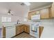 Open kitchen with wood cabinets, white appliances, and a breakfast bar overlooking the living area at 15962 W Gibson Ln, Goodyear, AZ 85338