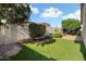 Well-manicured backyard featuring lush artificial grass, mature trees, shrubs and bench at 16466 W Lariat Ln, Surprise, AZ 85387
