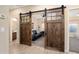 View of living room through rustic barn doors, couch with decorative pillows, and hardwood flooring at 16466 W Lariat Ln, Surprise, AZ 85387