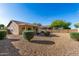 The backyard includes desert landscaping, a covered patio, tan exterior, and tile roof at 20717 N 104Th Ln, Peoria, AZ 85382