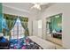 Light-filled bedroom with a floral-patterned bed, mirrored closet doors, and large windows with decorative curtains at 2801 N Litchfield Rd # 37, Goodyear, AZ 85395